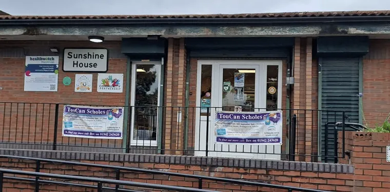 The front of Sunshine House in Scholes, a brick building with a dark grey entrance